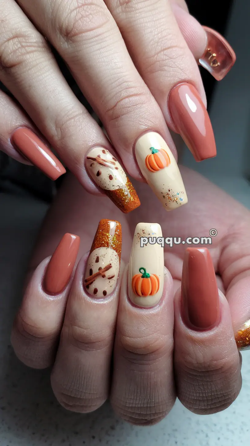 Close-up of hands with autumn-themed nail art, featuring pumpkins, sparkles, and cinnamon sticks on a mix of beige and brown nails.