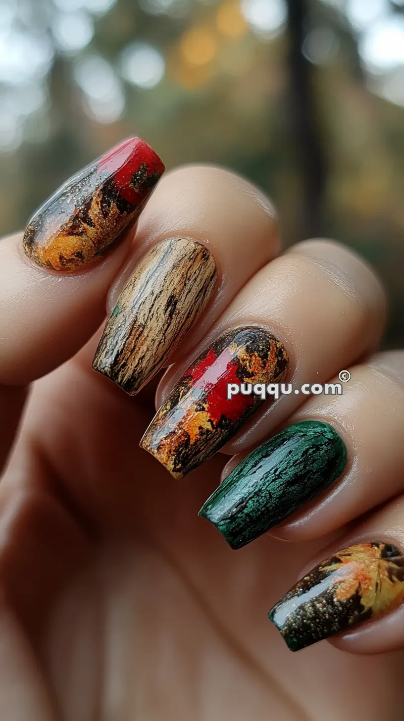 Close-up of a hand with long nails featuring autumn-themed nail art, including designs resembling tree bark, red and green leaves, and fall foliage.