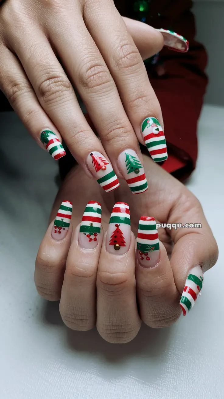 Fingernails with festive Christmas-themed nail art, featuring red and green stripes, Christmas trees, and holly designs.