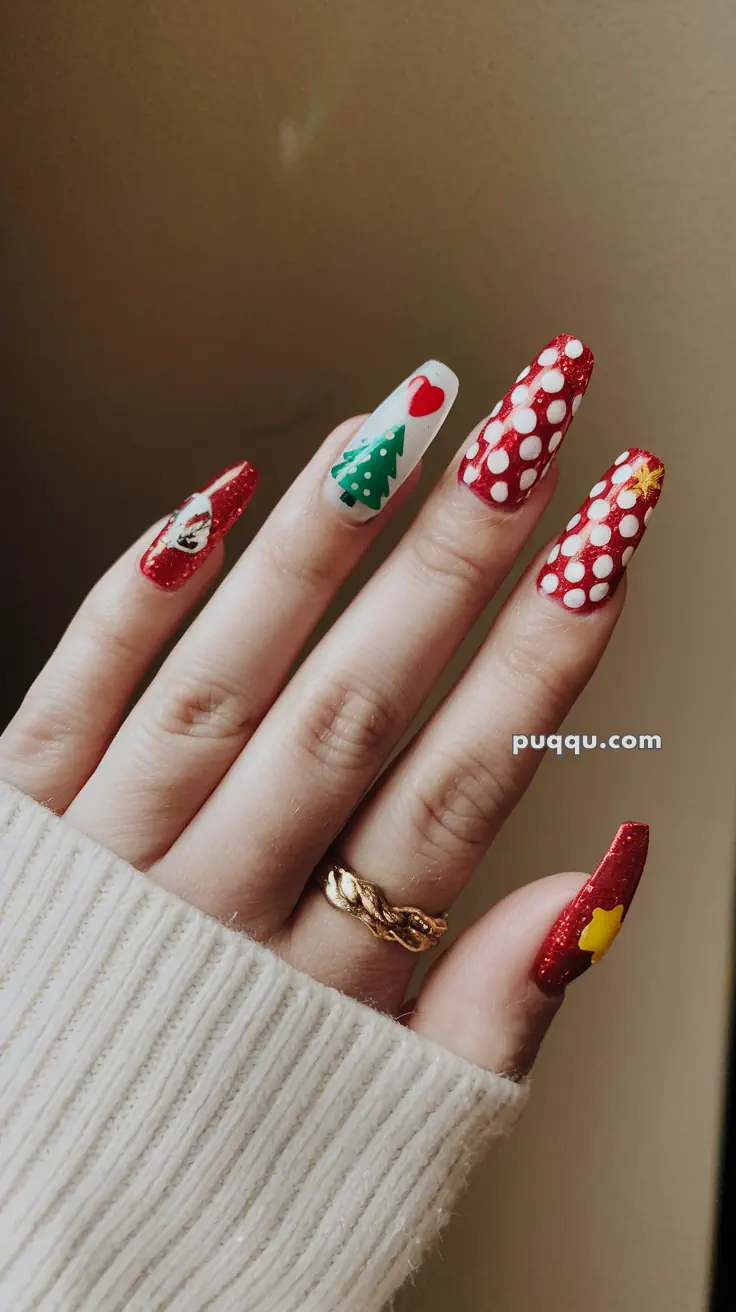 Hand with festive nail art designs including Christmas tree, hearts, polka dots, and stars.