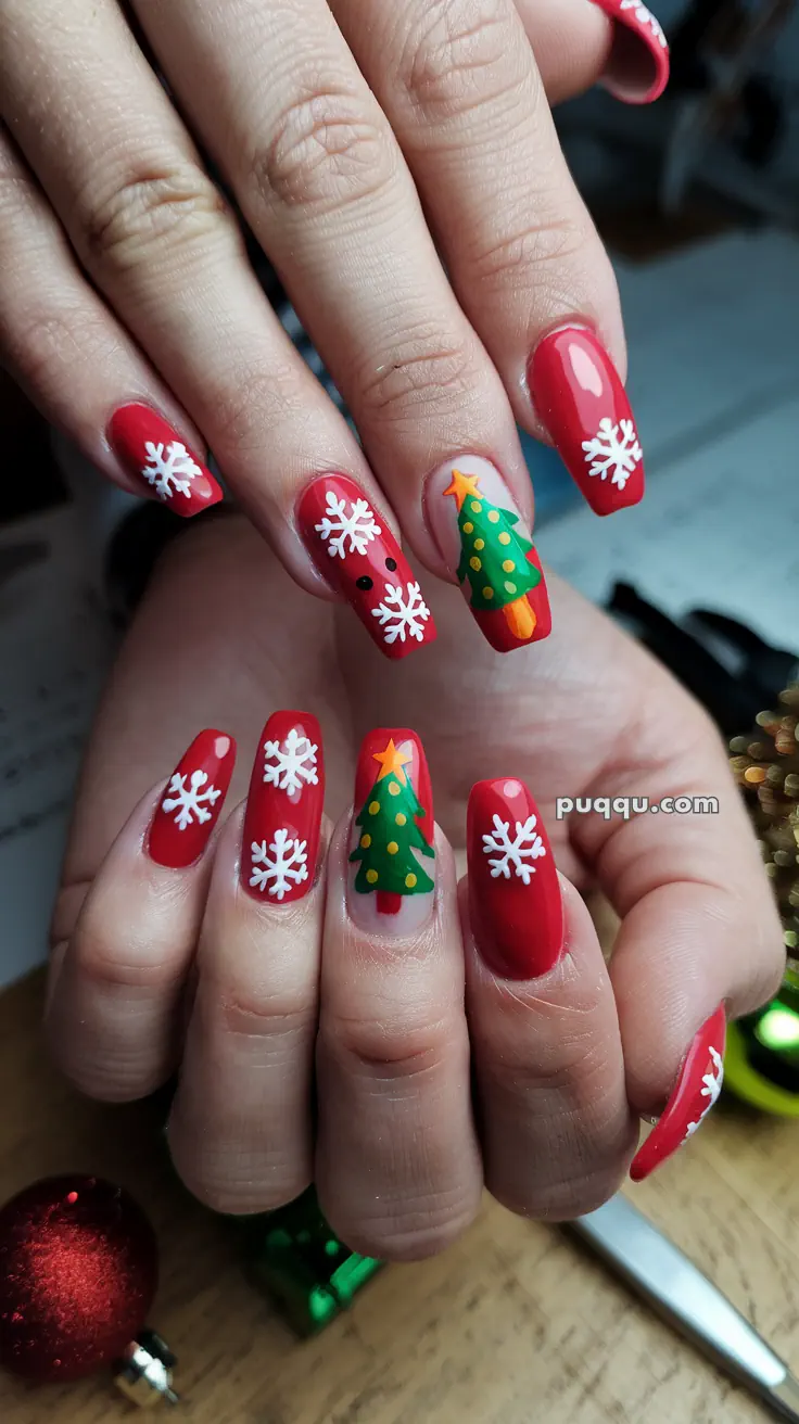 Red Christmas-themed nail art with white snowflakes and green Christmas tree designs.