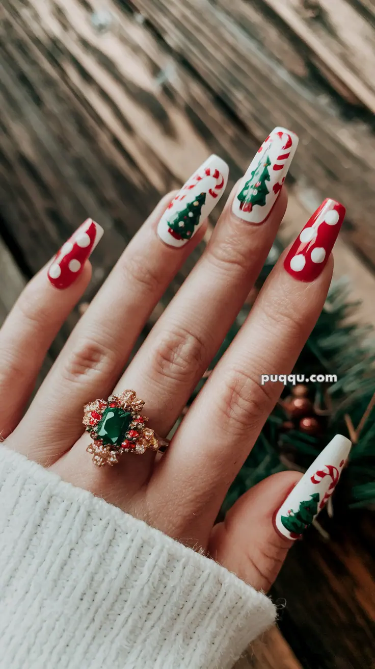 Festive nail art with Christmas tree and candy cane designs, featuring a hand wearing a decorative green gemstone ring.