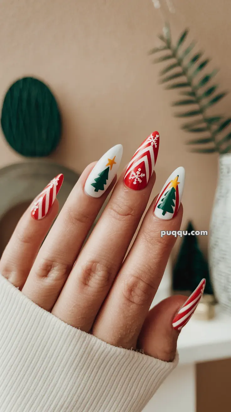 Hand with long nails featuring Christmas-themed designs, including red and white stripes, snowflakes, and Christmas trees.