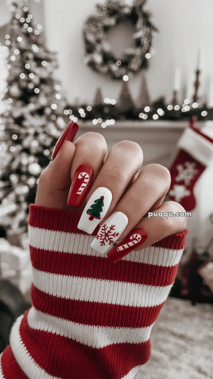 A hand with festive, Christmas-themed nail art featuring candy canes, a Christmas tree, and a snowflake, wearing a red and white striped sleeve.