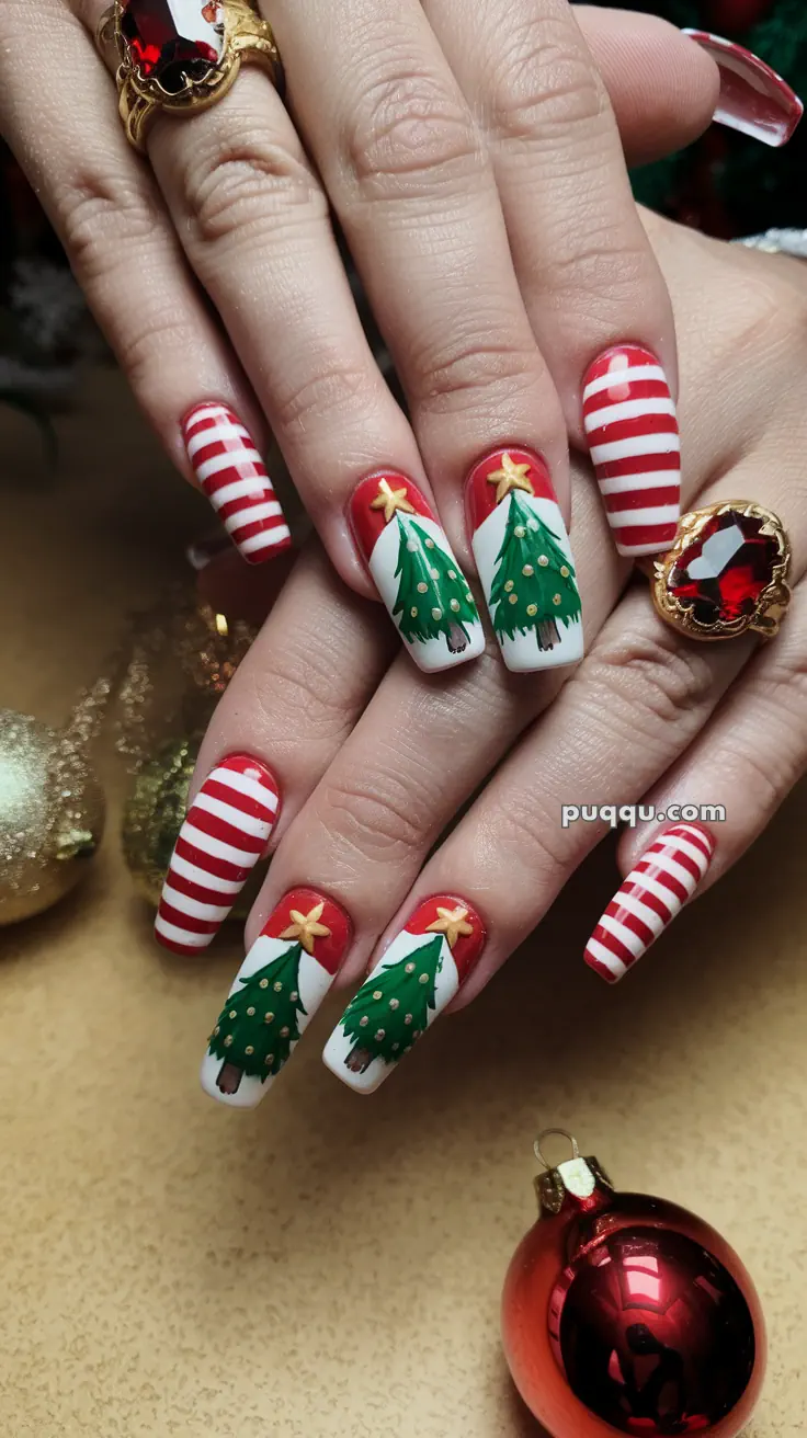 Festive nails with red and white stripes, adorned with Christmas tree designs and gold star accents, accompanied by a red gemstone ring.