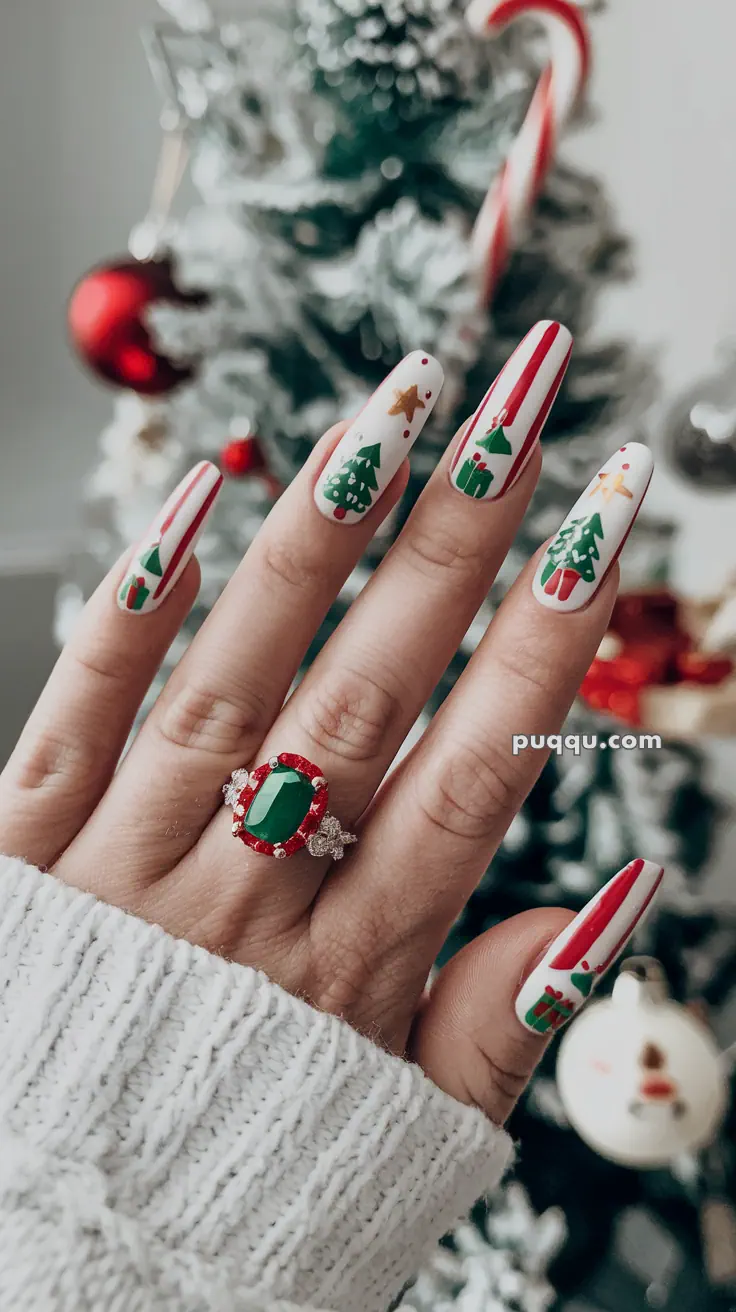 Fingernails with festive Christmas designs and a hand wearing an emerald ring against a blurred Christmas tree background.