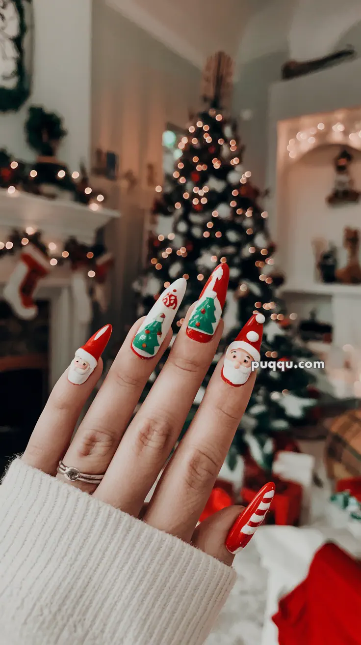 A hand with festive Christmas-themed nail art featuring Santa Claus, Christmas trees, and a candy cane, in front of a decorated Christmas tree.