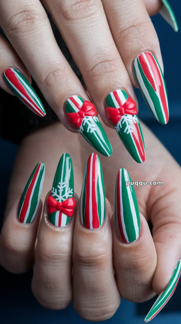 Fingernails with Christmas-themed nail art, featuring red, green, and white stripes, embellished with red bows and white snowflake designs.