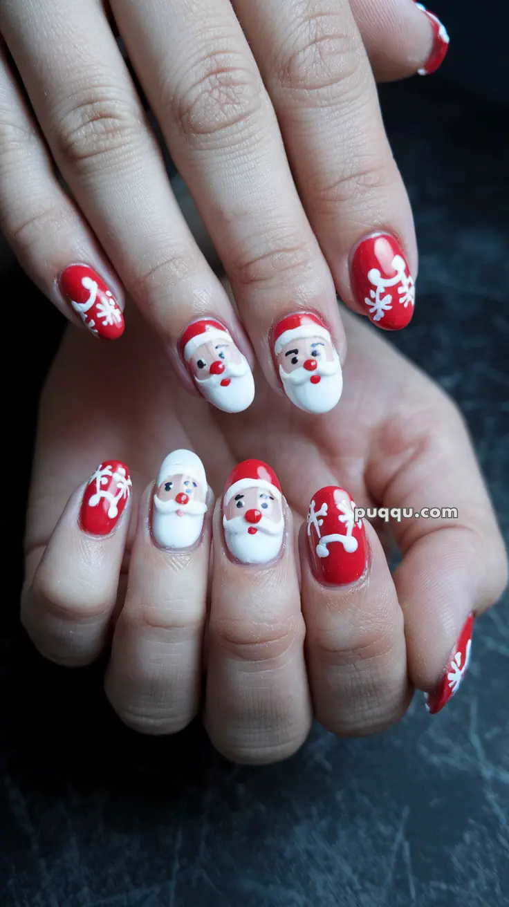 Close-up of hands with festive nail art featuring Santa Claus faces and snowflakes on red backgrounds.