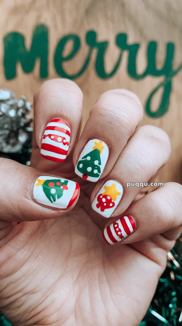 Fingernails painted with Christmas-themed designs, including striped patterns, a tree, and ornaments.