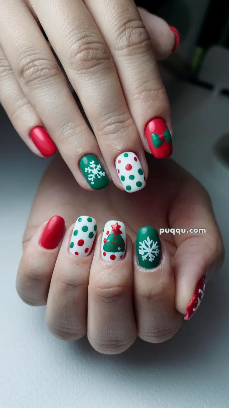 Festive nail art with red, green, and white designs featuring snowflakes, polka dots, a Christmas tree, and a bow.