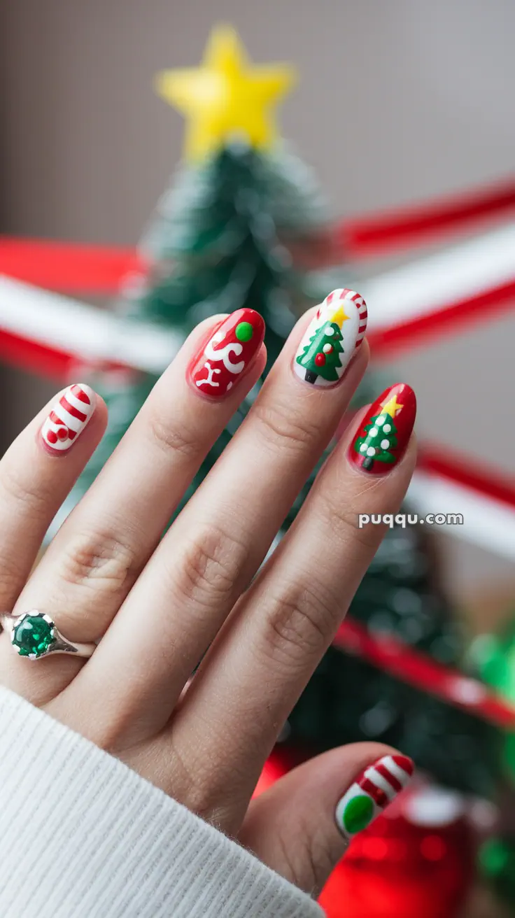 Hand with Christmas-themed nail art including candy canes and Christmas trees, wearing a ring with a green stone, against a festive background.