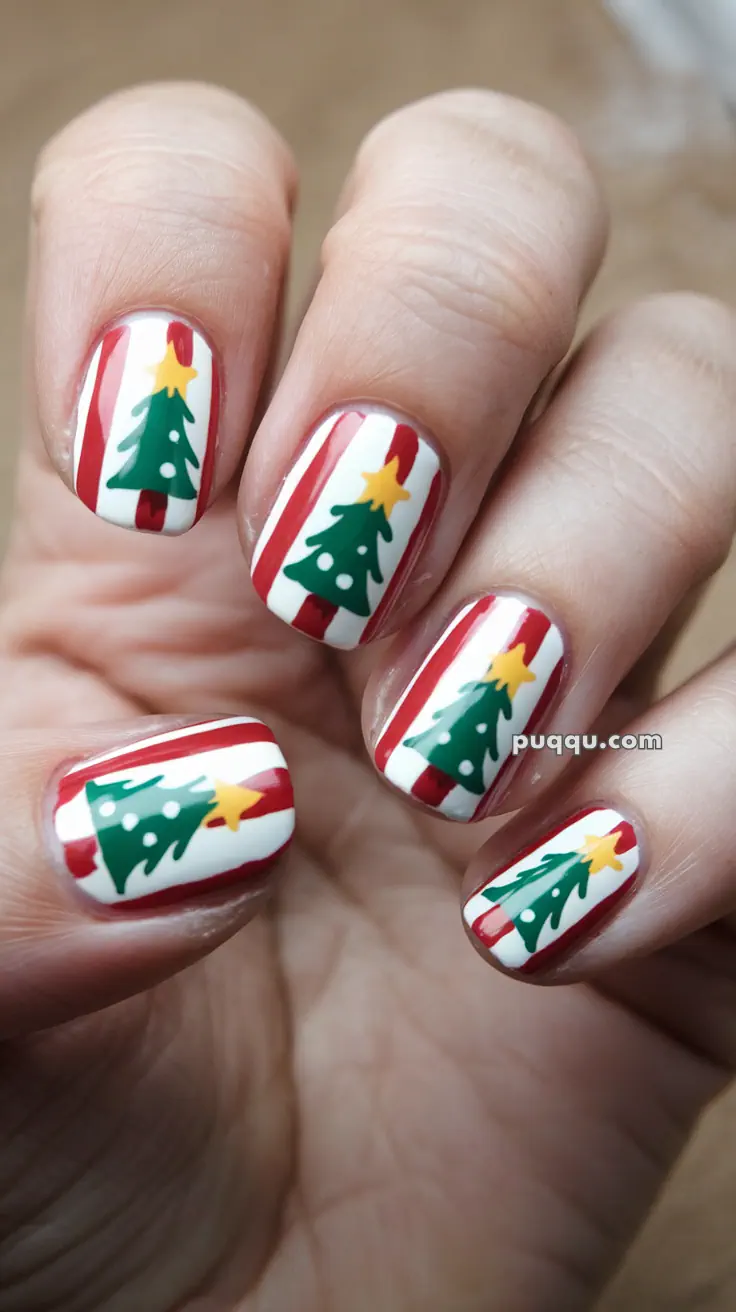 Fingernails with Christmas-themed nail art, featuring green trees with yellow stars and red stripes on a white background.