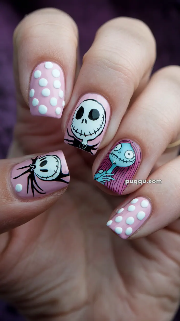 Close-up of hand with pink nails featuring white polka dots and Halloween-themed nail art of a skull and a character with long hair.