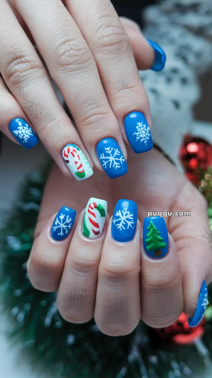 Blue and white Christmas-themed nail art featuring snowflakes, candy canes, and a Christmas tree design.