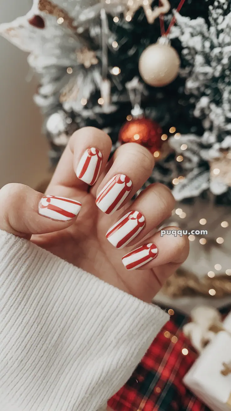 Christmas-themed nail art with red and white stripes in front of a festive holiday background.