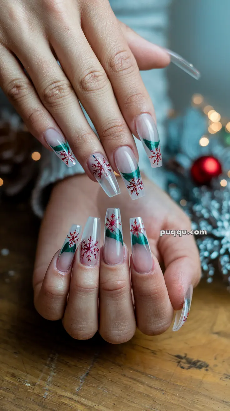 Hands with long nails decorated with red snowflakes and green accents.