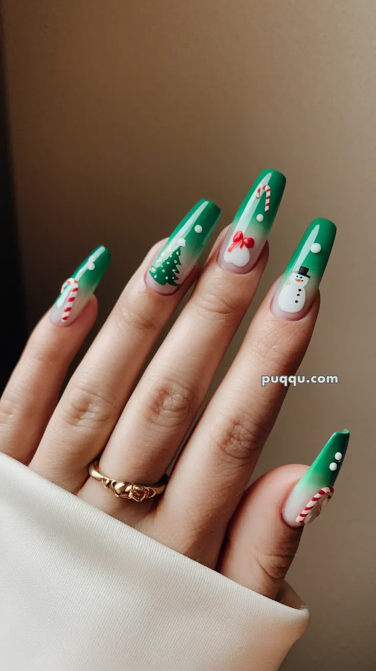 Hand with long green Christmas-themed nail art featuring candy canes, a snowman, a tree, and bows.