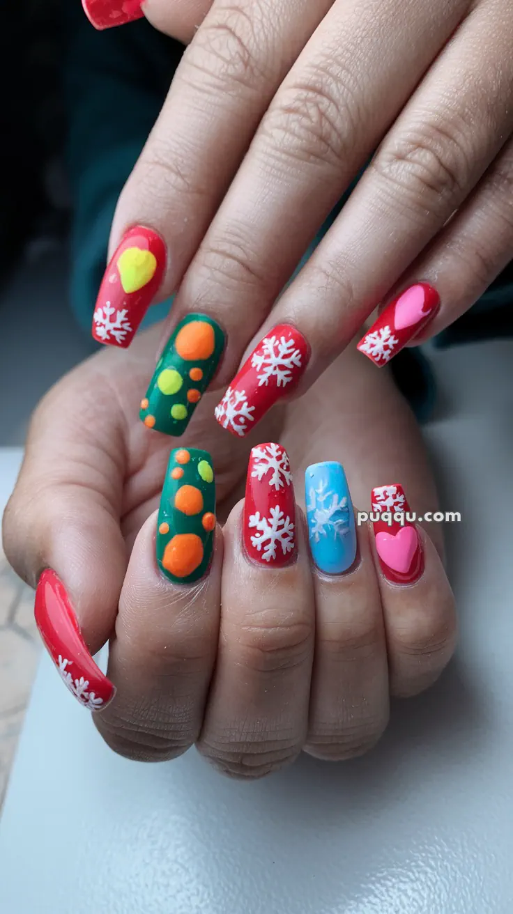 Hands with colorful nail art, featuring snowflakes, hearts, and circle patterns in red, blue, and green.