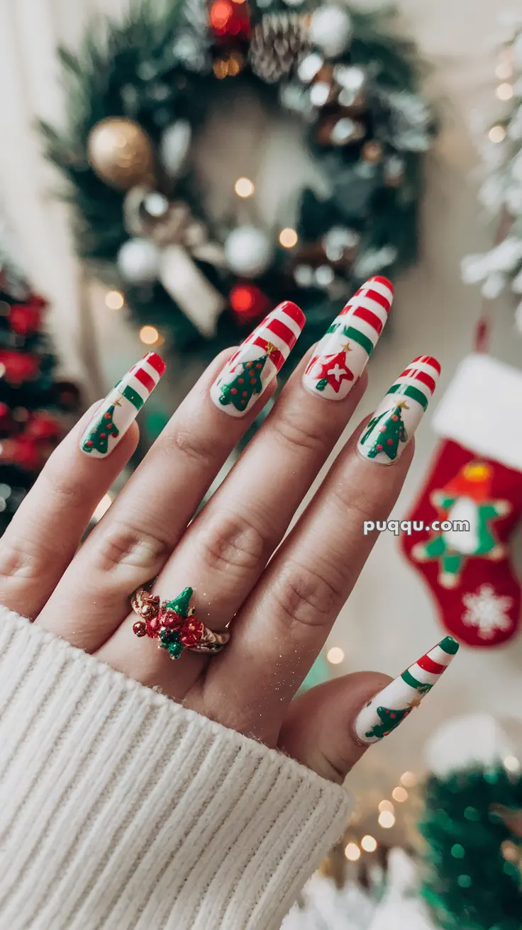 A hand with Christmas-themed nail art featuring red and white stripes, Christmas trees, and stars, wearing a festive ring against a holiday decor background.