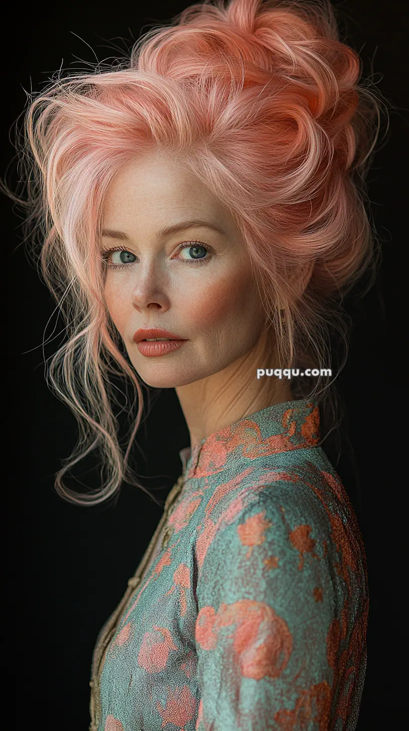 A woman with pink hair in an updo wears a patterned dress, looking towards the camera.