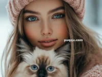 Woman wearing a pink knit hat and scarf holding a fluffy cat with blue eyes.