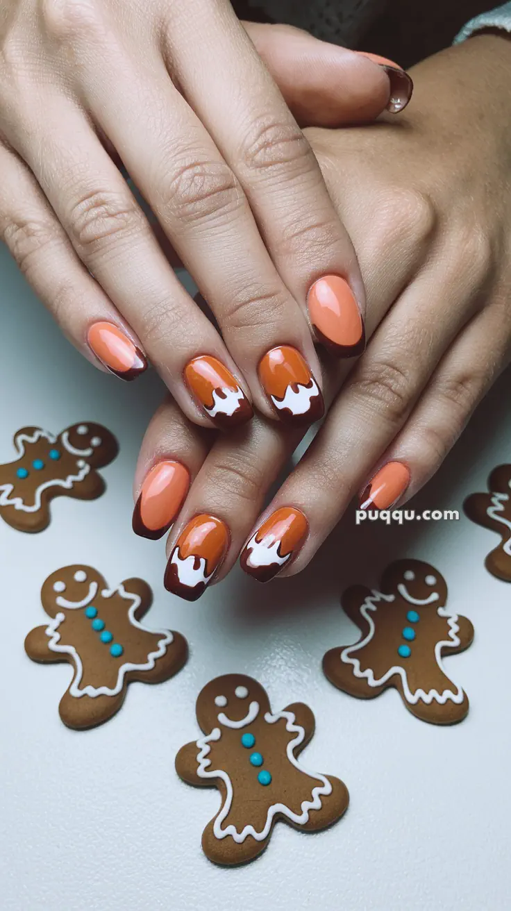 Hands with gingerbread-themed nail art surrounded by gingerbread cookies.