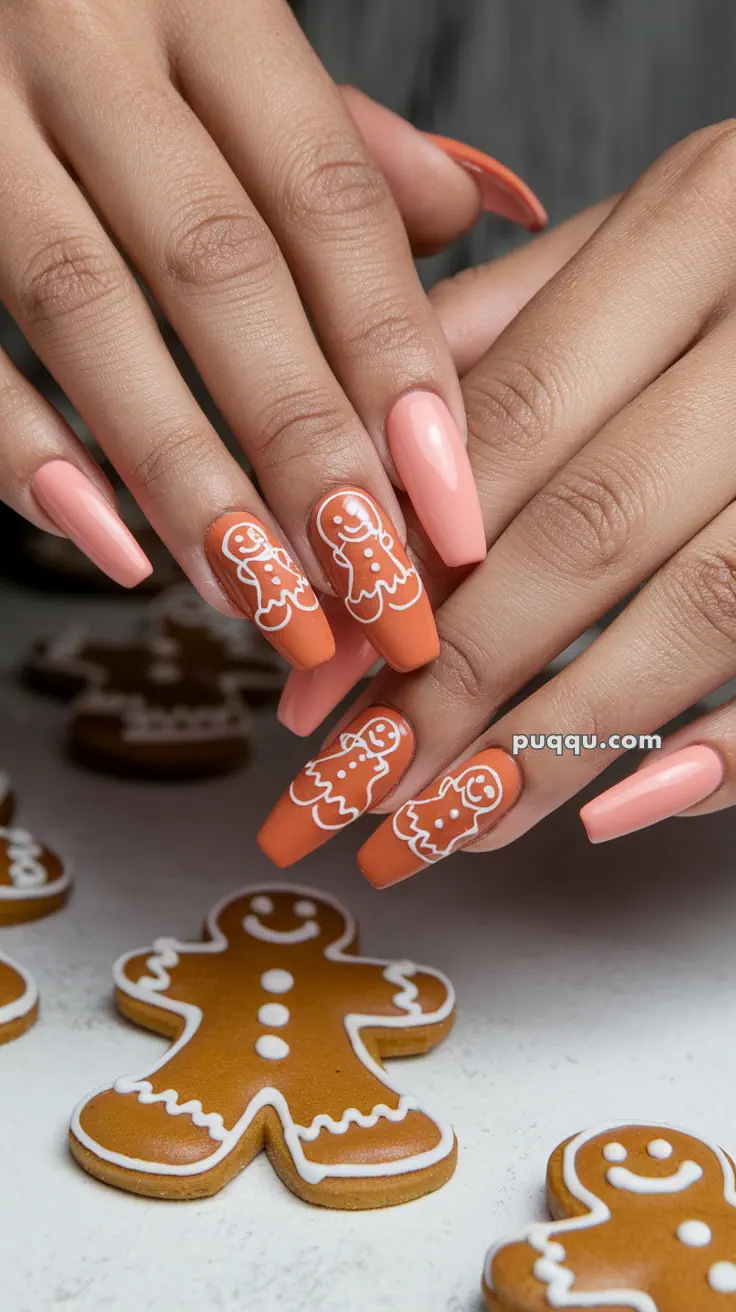 Close-up of hands with long nails painted in peach and orange, featuring gingerbread man designs, surrounded by gingerbread cookies.