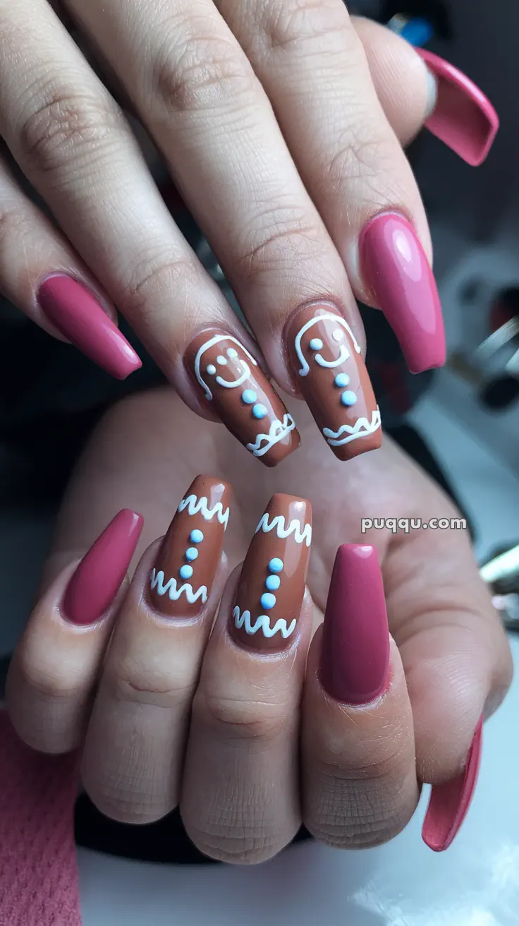 Close-up of hands with long, pink and brown nails featuring white gingerbread man designs.