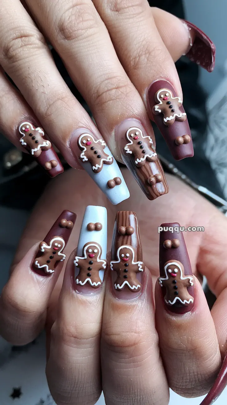 Close-up of long nails with gingerbread man designs and chocolate-themed nail art.