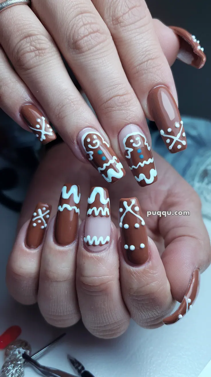 Brown and white gingerbread-themed nail art with gingerbread men and decorative patterns.