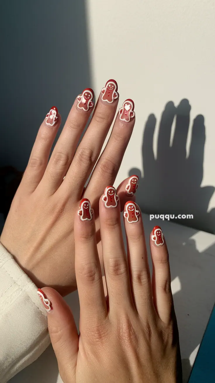 Close-up of hands with gingerbread man nail art on fingers.