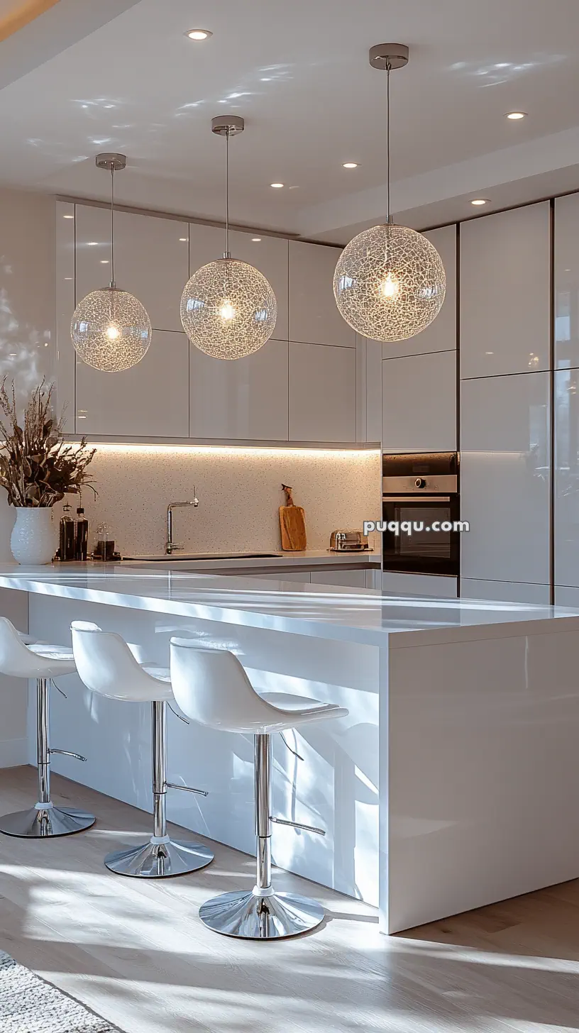 Modern kitchen with white cabinets, a countertop with bar stools, and three pendant lights above.