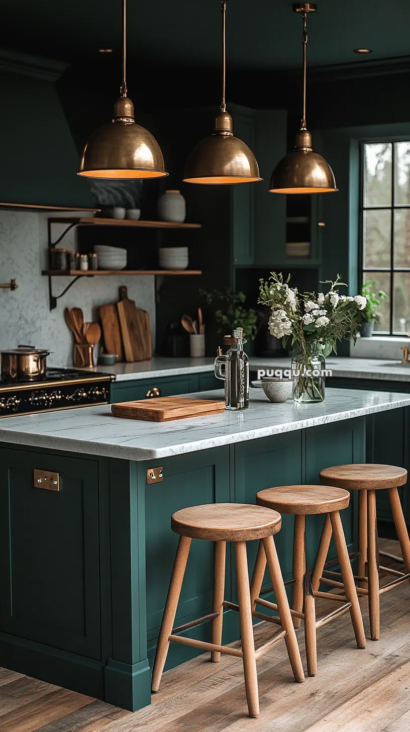 A modern kitchen with dark green cabinetry, brass pendant lights, a marble island, and wooden stools.