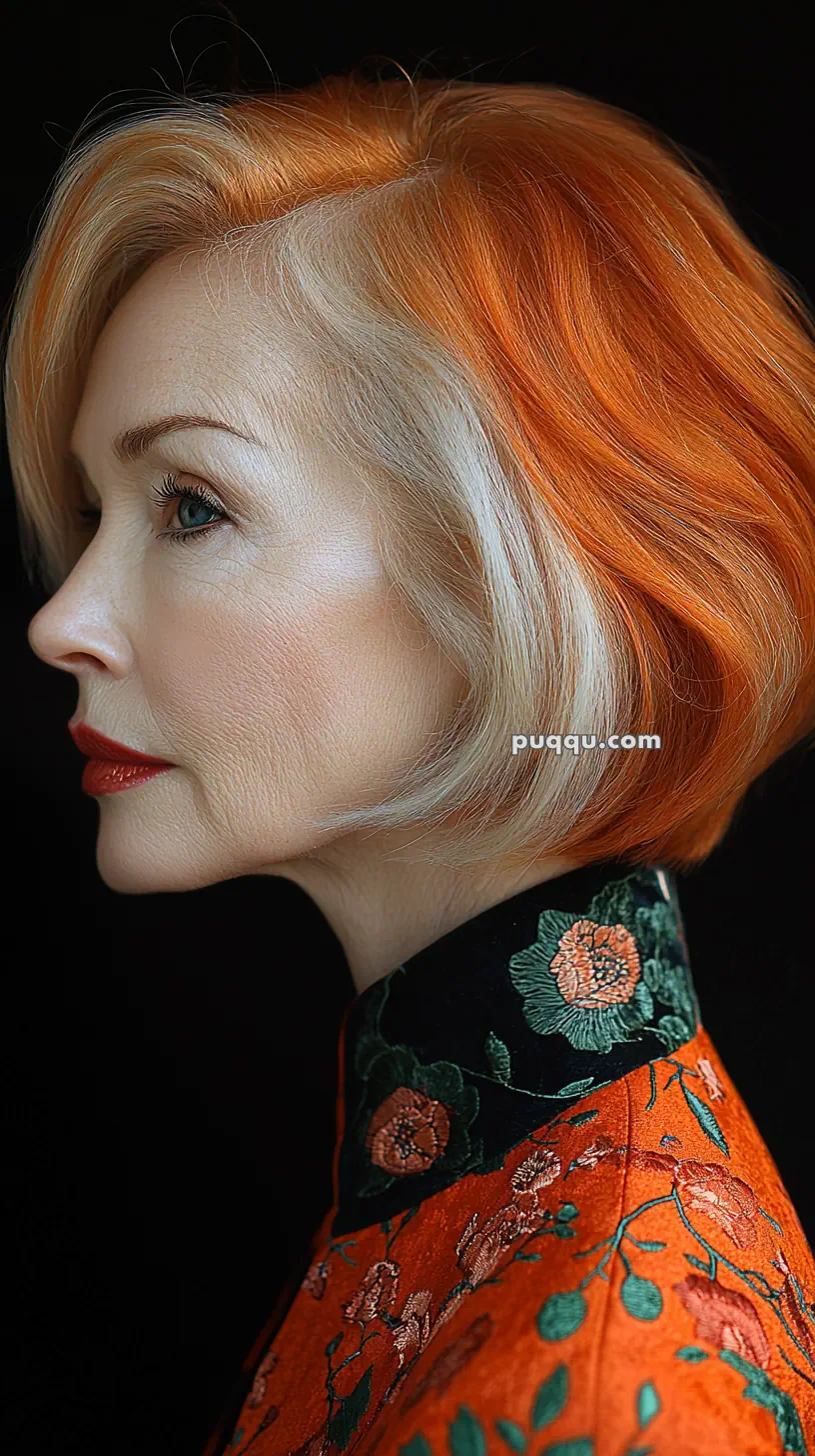 Profile view of a woman with orange and blonde hair, wearing an embroidered floral outfit.