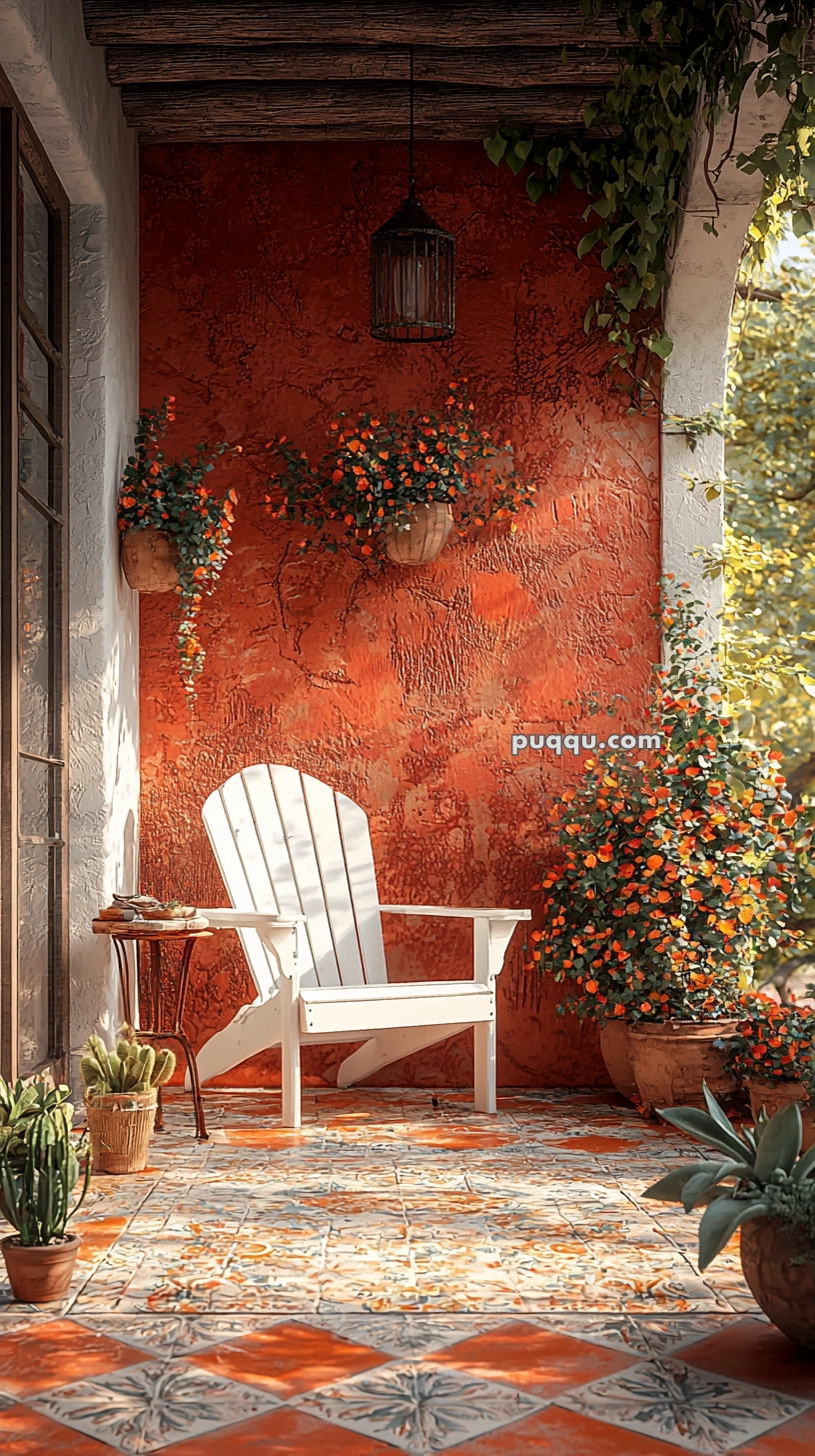 A cozy patio with a white Adirondack chair on colorful tiled flooring, surrounded by potted plants and flowers against a warm, textured red wall.