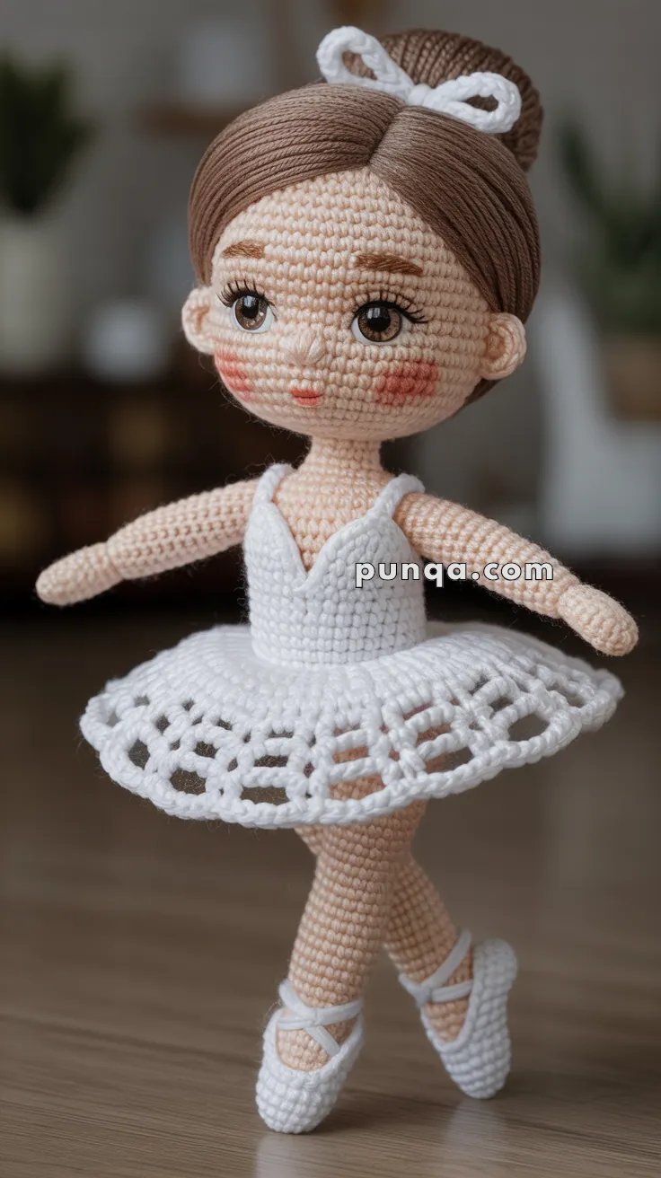 A crocheted doll dressed as a ballerina wearing a white tutu and ballet shoes, standing on a wooden surface with a blurred background.