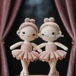 Two crocheted ballerina dolls in pink tutus stand side by side on a wooden platform, with stage curtains and a spotlight in the background.