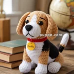 A crocheted dog plush toy resembling a beagle, labeled "Buddy," sits on a wooden table next to a stack of books and a globe.
