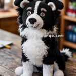 A crocheted black and white dog plush toy with realistic features sits on a wooden table, with a blurred background of a room and plants.