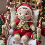 A crocheted baby doll dressed in a festive red and green outfit with a pacifier, seated in a decorative chair adorned with colorful yarn balls. The chair has a blanket that reads 'Wishing you a Sweet Christmas.' A Christmas tree and wrapped gifts are in the background, creating a holiday scene.