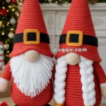 Two crocheted gnome figures with red hats, white beards, and black boots stand in front of a festive Christmas backdrop with a decorated tree and presents.