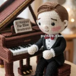 A crocheted doll wearing a tuxedo is sitting on a stool in front of a crocheted grand piano with sheet music titled 'Für Elise.' The doll and piano are made with detailed crochet work, featuring a brown hair, black suit, and a red bow tie on the doll.