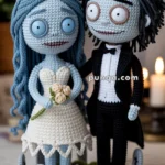 Crocheted figurines of a bride and groom with skeletal features, standing on a round base decorated with small tombstones and green edging.