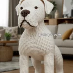 A large, crocheted white dog plush stands on a wooden floor in a cozy living room.