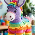 A colorful crocheted donkey piñata hanging by a pink string, featuring vibrant stripes of purple, blue, green, yellow, orange, and pink, with a smiling face and large ears.