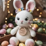 A crocheted bunny toy with colorful flowers on its ears sits among pastel-colored Easter eggs and fairy lights, with a "happy Easter" tag around its neck.