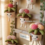 A collection of colorful, crocheted plant pots with smiling faces and dangling legs, each filled with crocheted flowers and leaves, hanging on a wooden ladder with a sign that reads 'Bloom Here.'