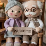 Crocheted dolls of an elderly couple sitting on a wooden rocking chair, holding a "Welcome" sign.
