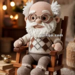 A crocheted doll resembling an elderly man with glasses and a white beard, wearing a sweater with a diamond pattern, sitting on a wooden rocking chair in a cozy room with warm lighting.